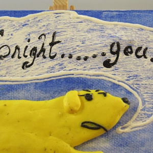 May include: A whimsical artwork featuring a yellow dog-like figure with black accents, set against a blue background. A white speech bubble contains the text "Tonight... you." The art piece has a playful, cartoonish style.