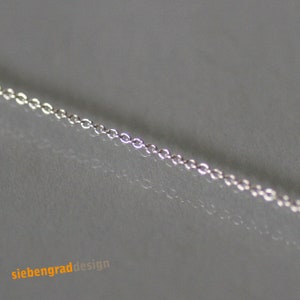 May include: A close-up of a silver chain necklace. The chain is made of small, delicate links.