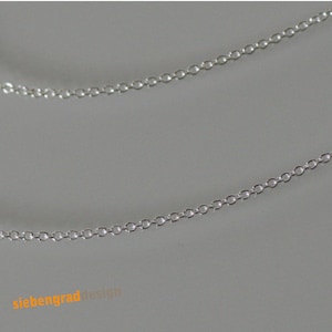 May include: A silver chain necklace with a delicate, linked design. The chain is shown in two layers, with the ends of the chain visible.