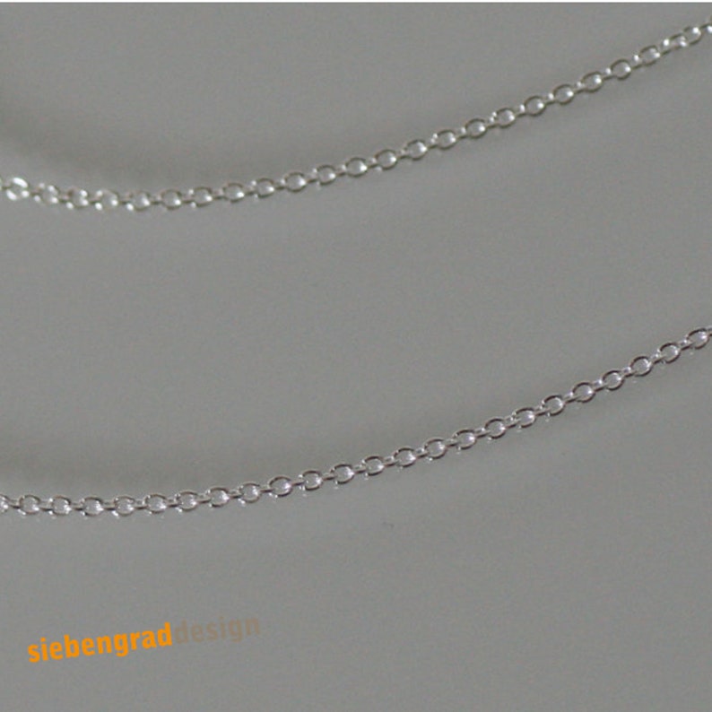 May include: A silver chain necklace with a delicate, linked design. The chain is shown in two layers, with the ends of the chain visible.