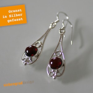 Könnte beinhalten: Ein Paar silberne Ohrhänger mit roten Granatsteinen. Die Ohrringe haben ein zartes, filigranes Design.