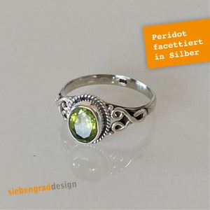 Könnte beinhalten: Ein silberner Ring mit einem grünen Peridot-Edelstein. Der Ring hat ein zartes, verziertes Design.