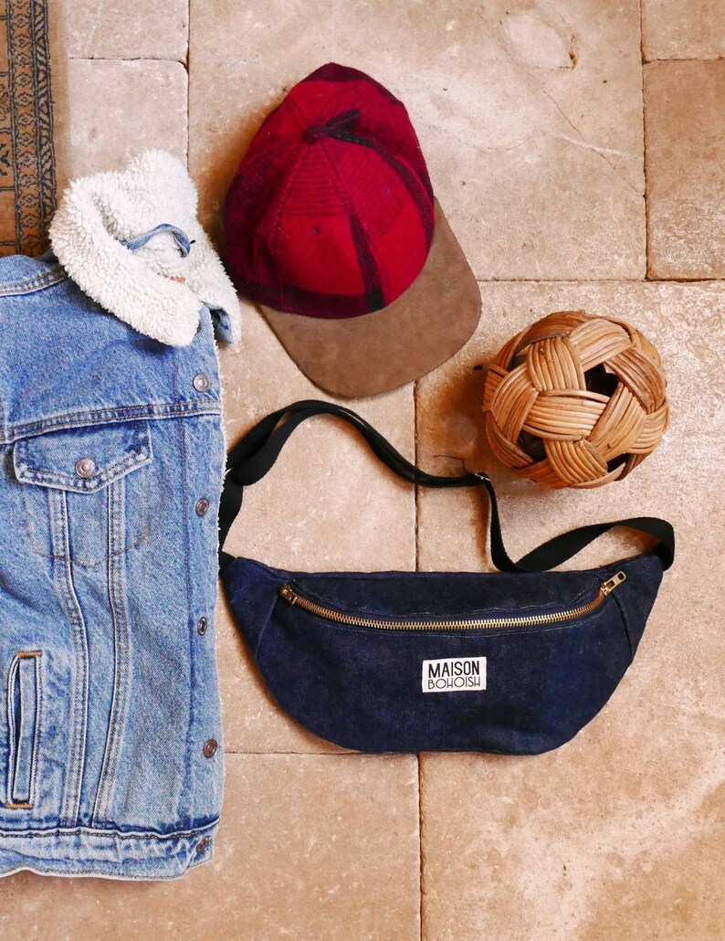 May include: A dark blue denim fanny pack with a gold zipper and a white label that says "MAISON BOHOISH".