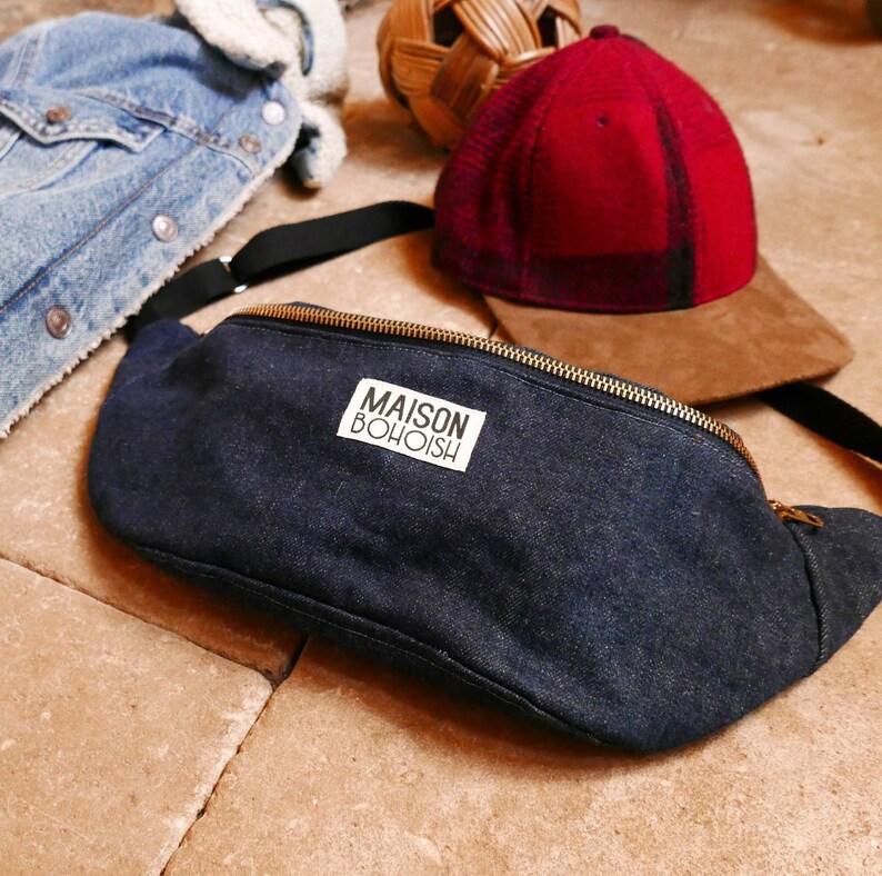 May include: A dark blue denim fanny pack with a gold zipper and a white label that reads "MAISON BOHOISH".
