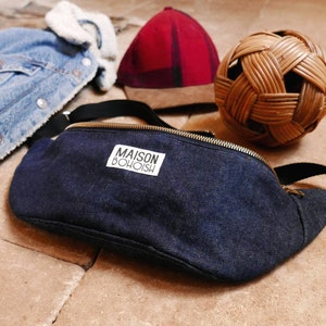 May include: A dark blue denim fanny pack with a white label that reads "MAISON BOHOISH".