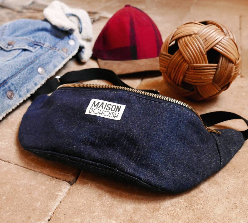 May include: A dark blue denim fanny pack with a white label that reads "MAISON BOHOISH".
