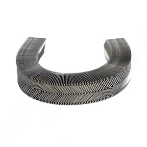 May include: A curved, metallic object with a corrugated surface, resembling a partial ring or horseshoe shape. The object has a series of parallel, zigzagging lines, creating a textured appearance. The color is a muted silver-gray, and the background is plain white.