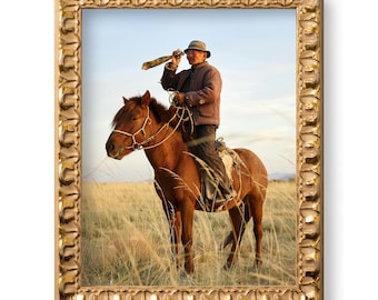 May include: A man in a brown jacket and hat rides a brown horse in a field of tall grass.