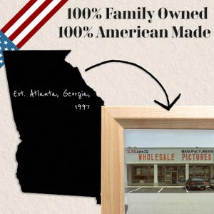 May include: A black and white image of a storefront with the text "US Art Co. Wholesale Manufacturers Pictures" above the entrance. The storefront is framed in wood and the image is set against a white background with the text "100% Family Owned 100% American Made" at the top.