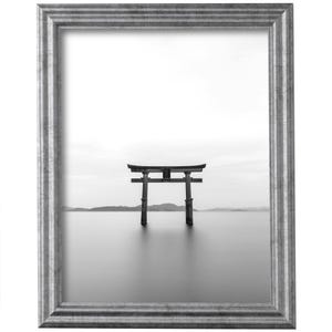 May include: A black and white photograph of a traditional Japanese torii gate, a wooden structure with two pillars and a crossbeam, standing in the water. The gate is surrounded by a calm, still body of water, and the background is a hazy, distant landscape.