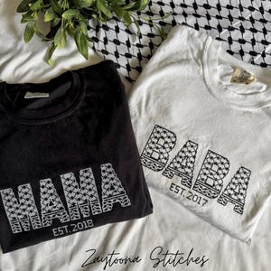 May include: Two t-shirts, one black and one white, with the words "MAMA" and "BABA" in a geometric design. The black shirt says "EST. 2018" and the white shirt says "EST. 2017". The text "Zaytoona Stitches" is at the bottom.