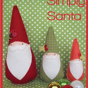 Könnte beinhalten: Drei Filz-Weihnachtsmann-Ornamente in Rot, Grün und Orange mit weißen Bärten und Knopfaugen. Die Ornamente befinden sich auf einem grün-weiß gepunkteten Hintergrund. Der Text "Simply Santa" ist oben im Bild in Rot geschrieben.