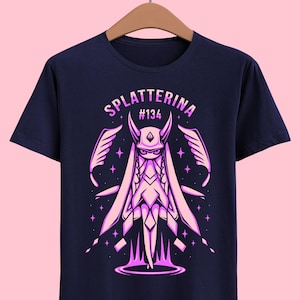May include: A navy blue t-shirt with a pink graphic of a character with wings and horns. The text "splatterina #134" is above the character.