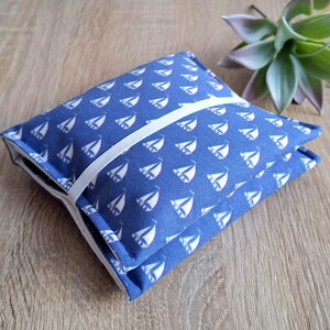 Könnte beinhalten: Ein blauer Stoff-Taschentuchbox-Bezug mit einem weißen Segelboot-Muster. Der Bezug hat ein weißes Gummiband, um ihn geschlossen zu halten.