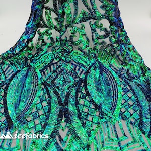 May include: Green and blue iridescent sequins on a black mesh fabric. The sequins are arranged in a geometric pattern.
