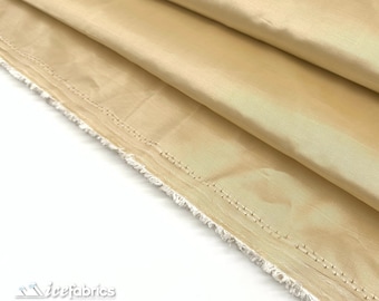 May include: A length of solid light gold fabric with a smooth, lustrous finish and a subtle sheen. The material is folded to create soft, cascading drapes, and the unfinished edge shows a frayed, white selvage with visible stitching.