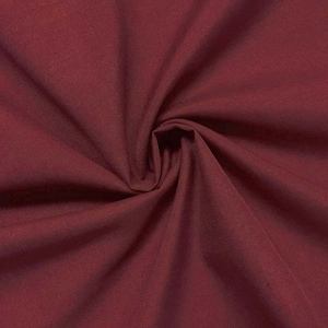 Puede incluir: Primer plano de una tela de color burdeos intenso con una textura suave. La tela está doblada y drapeada, mostrando su naturaleza suave y fluida.