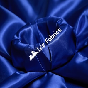 May include: Close-up of a royal blue satin fabric, folded and draped, with the text "Ice Fabrics" in white lettering.