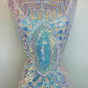 May include: A sheer fabric with iridescent sequins in a geometric pattern. The sequins are in shades of blue, purple, and white.