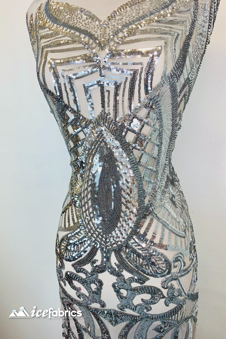 May include: Silver sequined fabric with a geometric pattern. The fabric is sheer and has a delicate, intricate design.