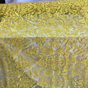 May include: Yellow embroidered lace fabric with a floral pattern. The lace is delicate and has a soft, flowing texture.