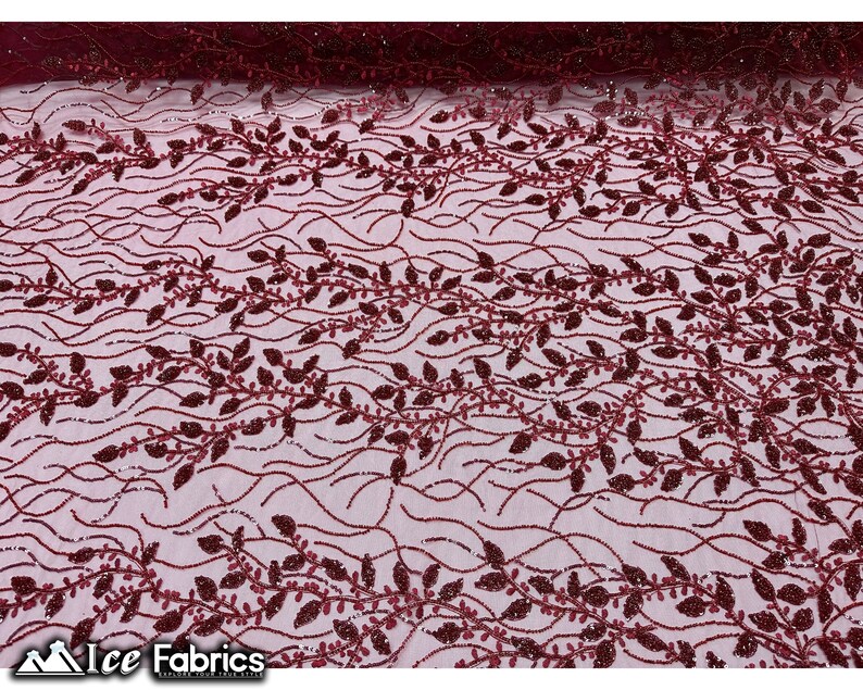 Puede incluir: Tela de encaje de color rojo burdeos con un delicado patr&oacute;n floral. La tela tiene un brillo sutil y es perfecta para crear prendas o accesorios elegantes.