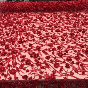 Puede incluir: Tela de encaje roja con cuentas y adornos florales 3D. La tela tiene una base de malla delicada y está adornada con numerosas flores rojas en relieve y texturadas.