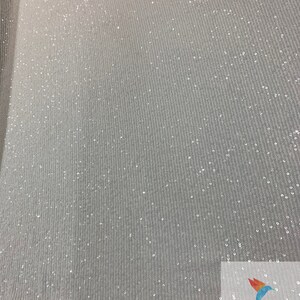 May include: White fabric with a subtle shimmer from small, evenly spaced sequins. The fabric has a slight texture, creating a ribbed effect. The fabric is shown against a white background.