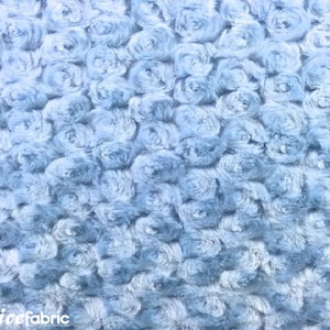 Könnte beinhalten: Nahaufnahme eines hellblauen Stoffes mit rosenartiger Textur. Der Stoff hat ein weiches, plüschiges Aussehen, wobei die Textur ein Muster aus wirbelnden, abgerundeten Formen erzeugt. Der Gesamteffekt ist eine dichte, strukturierte Oberfläche.