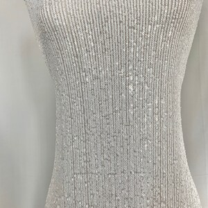 May include: White fabric with a vertical pattern of small, iridescent sequins.
