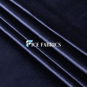 May include: Navy blue fabric with a soft, lustrous sheen. The fabric is draped in diagonal folds, creating shadows and highlights. The text "ICE FABRICS" is printed in white.