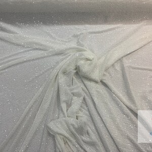 May include: White fabric with a subtle shimmer and a ribbed texture. The fabric is draped and folded, showing the texture and sheen.