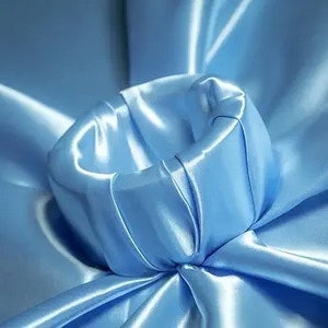 May include: A light blue satin fabric with a gathered, circular shape in the centre.