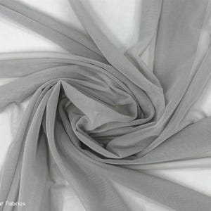 Könnte beinhalten: Nahaufnahme eines hellgrauen, durchsichtigen Netzstoffes. Der Stoff ist weich und zart, mit einer feinen, gleichmäßigen Webart. Er ist perfekt für eine Vielzahl von Bastelprojekten, wie z. B. die Herstellung von Vorhängen, Tischdecken oder Kleidung.