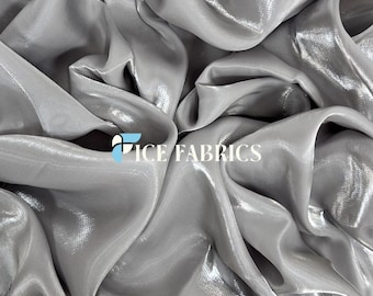 May include: Silver iridescent fabric with a subtle sheen. The fabric is smooth and silky, with a delicate drape.  The fabric is perfect for creating elegant garments, home decor, and accessories.