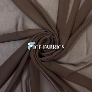 Può includere: Un tessuto marrone scuro trasparente drappeggiato in un motivo a vortice centrale. Il materiale ha una qualità traslucida con pieghe visibili che si irradiano verso l'esterno. Il testo ICE FABRICS è stampato in bianco con un logo azzurro.