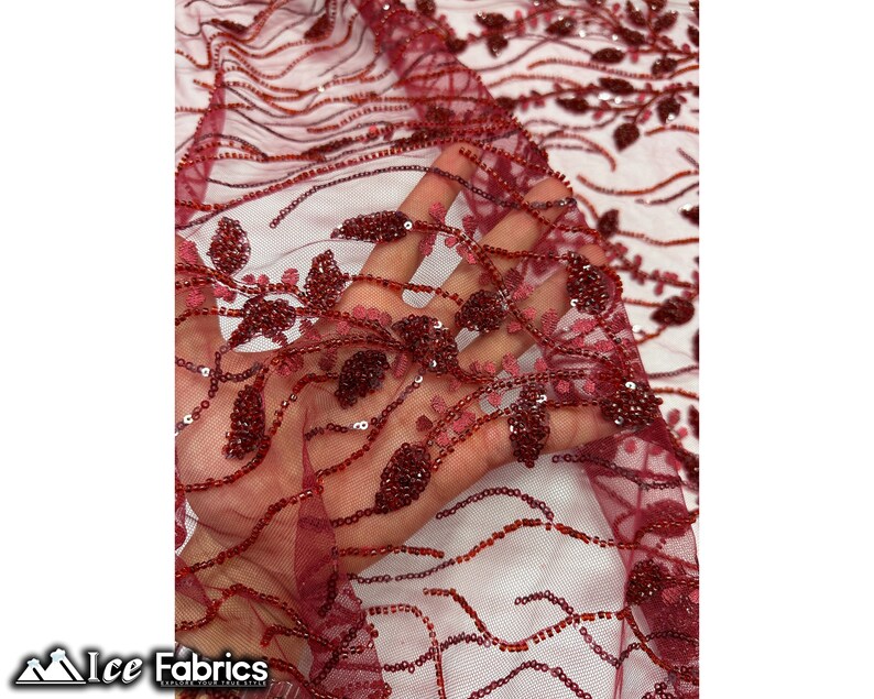 Puede incluir: Tela de encaje de color burdeos con cuentas y un dise&ntilde;o floral. La tela es transparente y tiene una textura delicada.