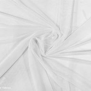 Op de afbeelding: Witte, doorschijnende stof met een zachte, delicate textuur. De stof is gedrapeerd en gevouwen, wat de vloeiende en luchtige kwaliteit laat zien.