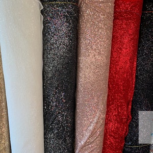 May include: A variety of sparkly fabrics in different colors, including gold, white, black, pink, red, and silver. The fabrics are all sequined and have a shimmering effect.