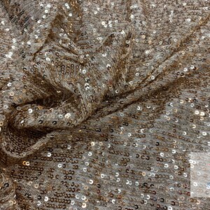 May include: Gold sequin fabric with a subtle shimmer. The fabric is woven with a fine mesh backing and features small, round sequins.