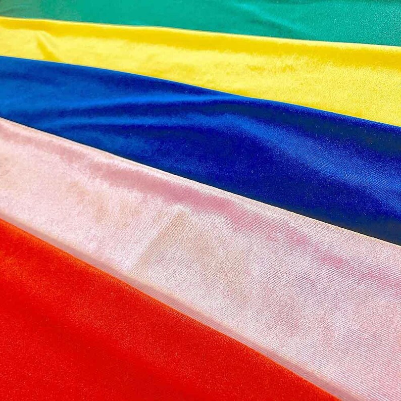 May include: A stack of six velvet fabric swatches in different colors, including red, pink, blue, yellow, and green.
