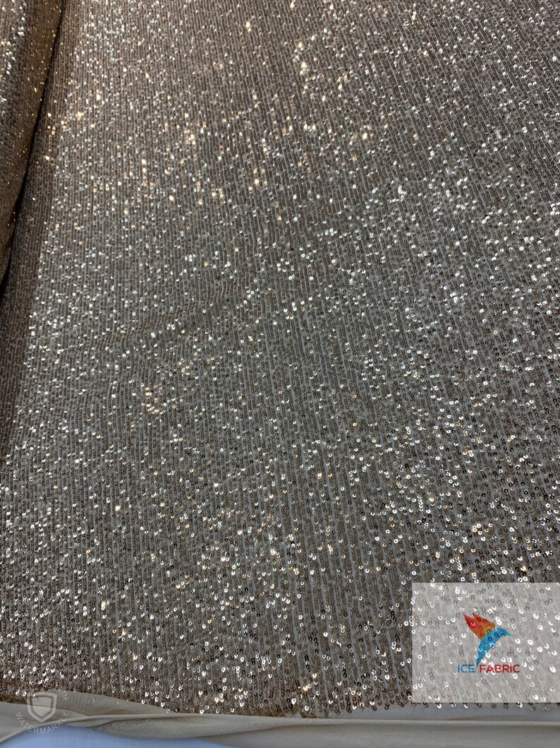 May include: A close-up of a gold sequined fabric with a subtle shimmer. The sequins are small and densely packed, creating a luxurious and glamorous look.