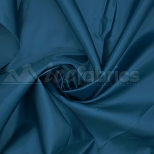 May include: A close-up of a deep blue satin fabric, showing its smooth texture and soft drape. The fabric is folded and arranged in a way that highlights its luxurious feel.