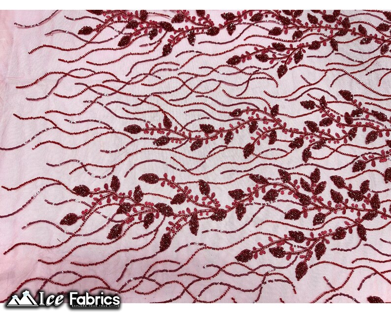 Puede incluir: Tela de encaje de color burdeos con cuentas y un delicado patr&oacute;n floral. La tela presenta peque&ntilde;as cuentas brillantes dispuestas en un dise&ntilde;o de enredadera con hojas.