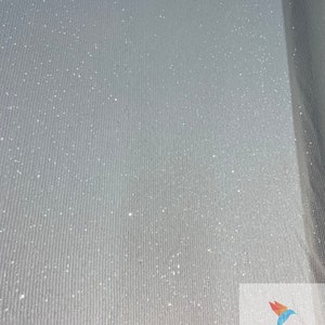 May include: White fabric with a subtle sparkle and a ribbed texture. The fabric is rolled up and the edge of the roll is visible. The text "ICE FABRIC" is visible in the bottom right corner of the image.