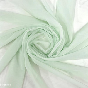 May include: Pale green tulle fabric, soft and sheer, with a delicate texture. The fabric is gathered and draped, showcasing its flowing nature.