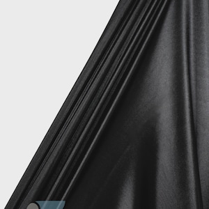 May include: A solid black fabric with a smooth, reflective, and satin-like finish. The material is draped in diagonal folds, creating deep shadows and highlights across the surface. The logo ICE FABRICS is printed in the bottom left corner.