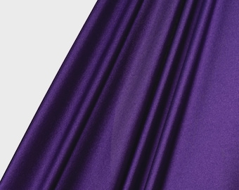 May include: A deep purple fabric with a smooth, slightly reflective surface and soft, vertical folds. The material displays a consistent, rich violet hue throughout, with a logo in the bottom left corner that reads ICE FABRICS.