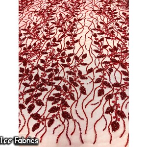 Puede incluir: Tela de encaje roja con cuentas con un patr&oacute;n floral. La tela tiene una base de malla transparente con peque&ntilde;as cuentas rojas y lentejuelas que forman un delicado dise&ntilde;o de hojas.