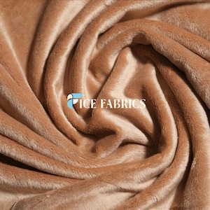 May include: A close-up shot of a soft, tan-coloured plush fabric. The material is folded and draped, creating a swirling pattern. The text "ICE FABRICS" is visible in the centre of the image.